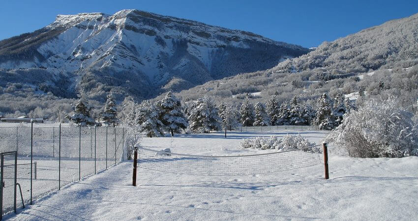 L’aire de jeux en hiver. Avec le terrain de tennis. Céüse en arrière-plan